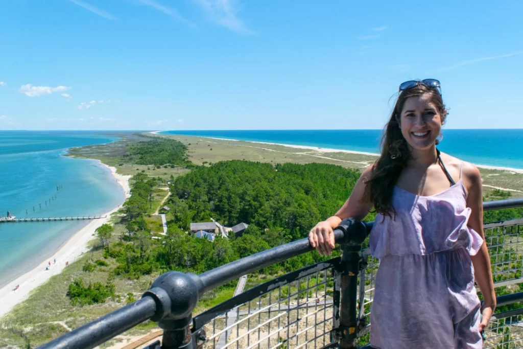 kate storm on top of cape lookout lighthouse in north carolina with barrier island and ocean visible behind her