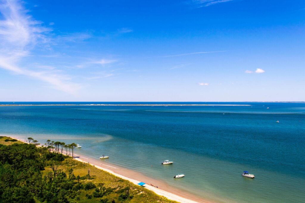 view of atlantic ocean and barrier islands from the top of cape lookout lighthouse, with boats visible inthe water below