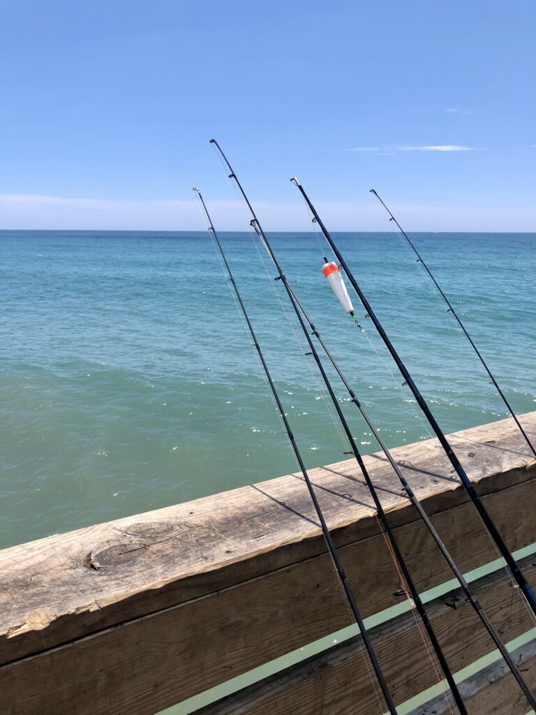 fishing poles leaning against the edge of oceanana pier in atlantic beach north carolina