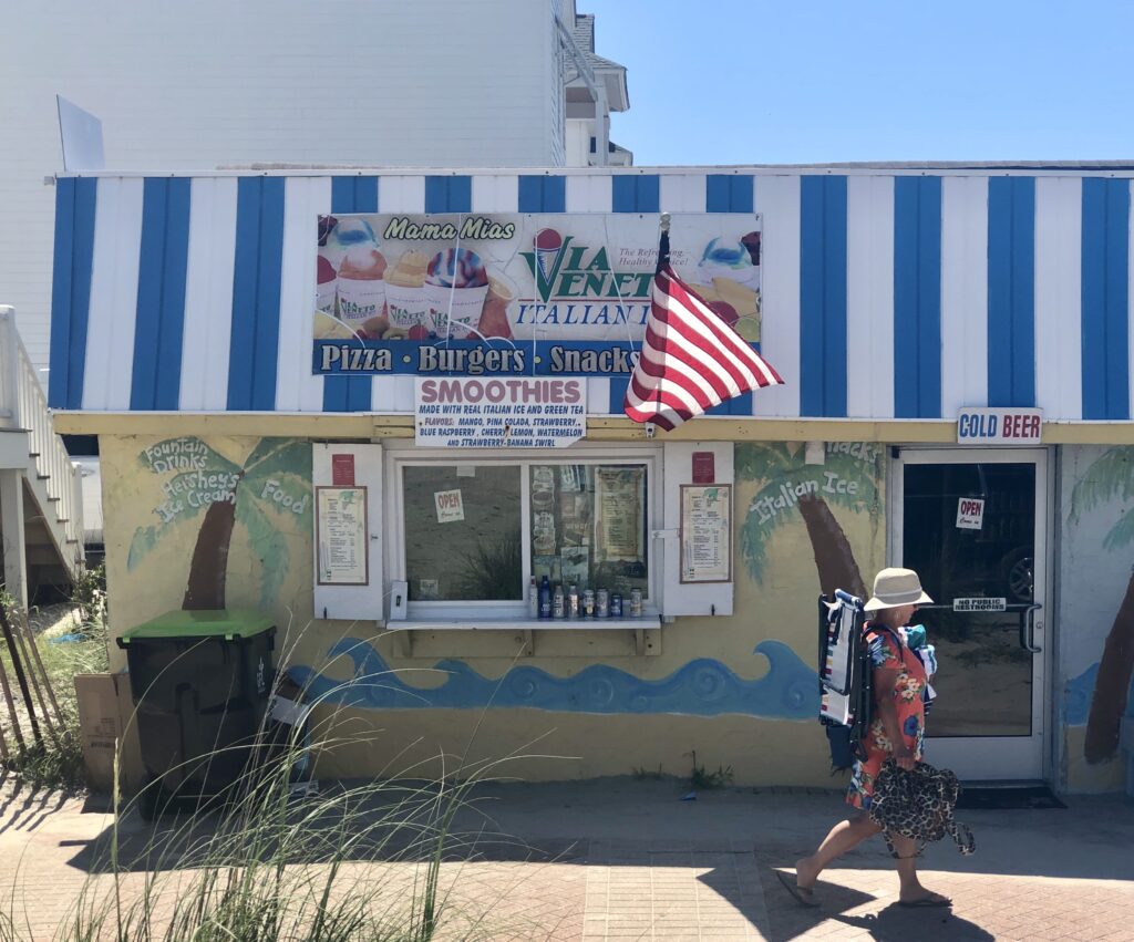 view of ice cream shop near the circle in atlantic beach nc with colorful decor and a beachgoer walking by