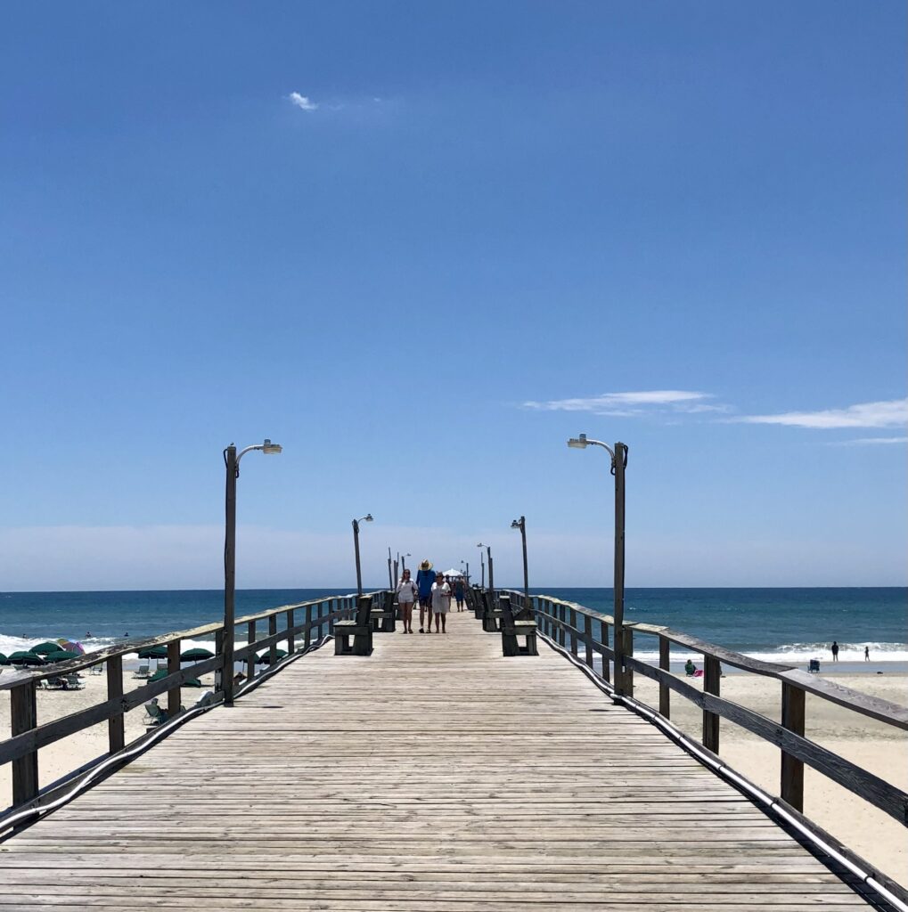 view looking down oceanana pier toward the ocean on a sunny summer day visiting atlantic beach nc